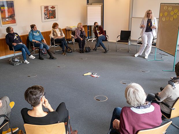 Menschen auf Stühlen hören einen Vortrag.