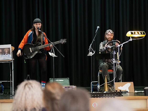 Zwei Menschen mit Instrumenten auf einer Bühne.